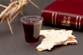Communion cup and bread beside a Bible